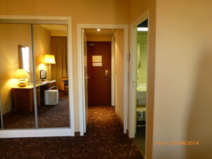 Armário espelhado à esquerda, um corredor (espaço que normalmente não encontramos habitualmente em nenhum hotel), e banheiro amplo à direita.