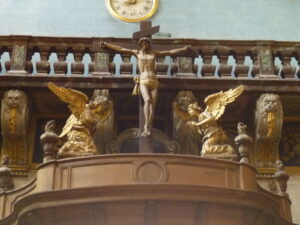 Imagem de Cristo cruxificado ladeado por dois anjos no estilo barroco.