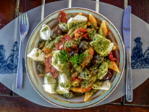 Penne, tomate seco, mussarela de búfala e alcaparras ao molho pesto.
